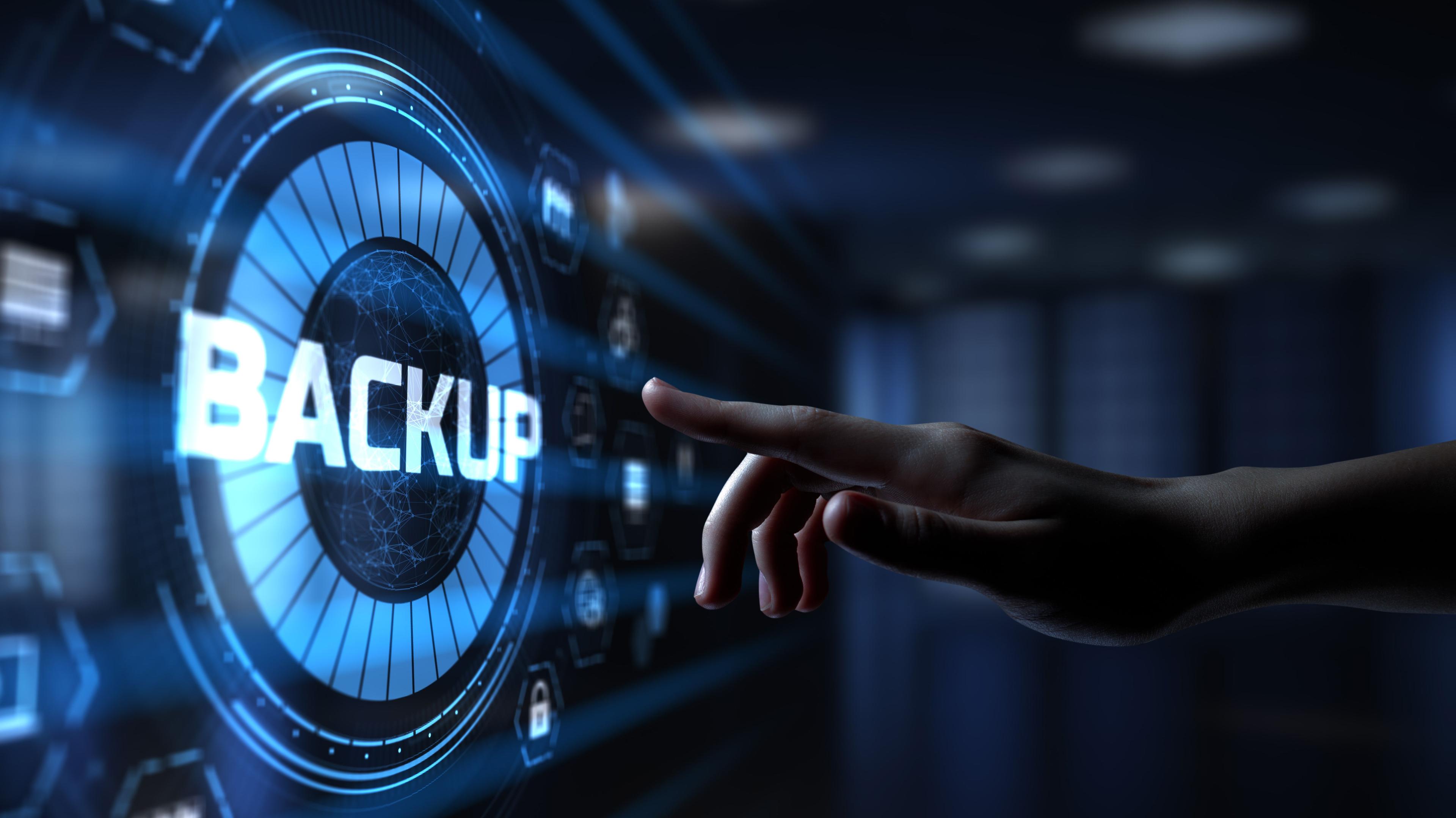 A hand is reaching out to touch a digital interface displaying the word "BACKUP" in large letters. The background features a futuristic, blue-toned digital environment with various icons and symbols, suggesting data storage themes.